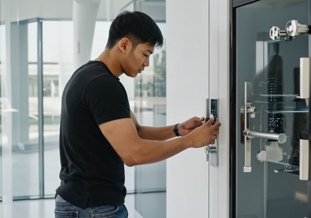 Man opent een modern digitaal deurslot in een gebouw met glazen wanden.