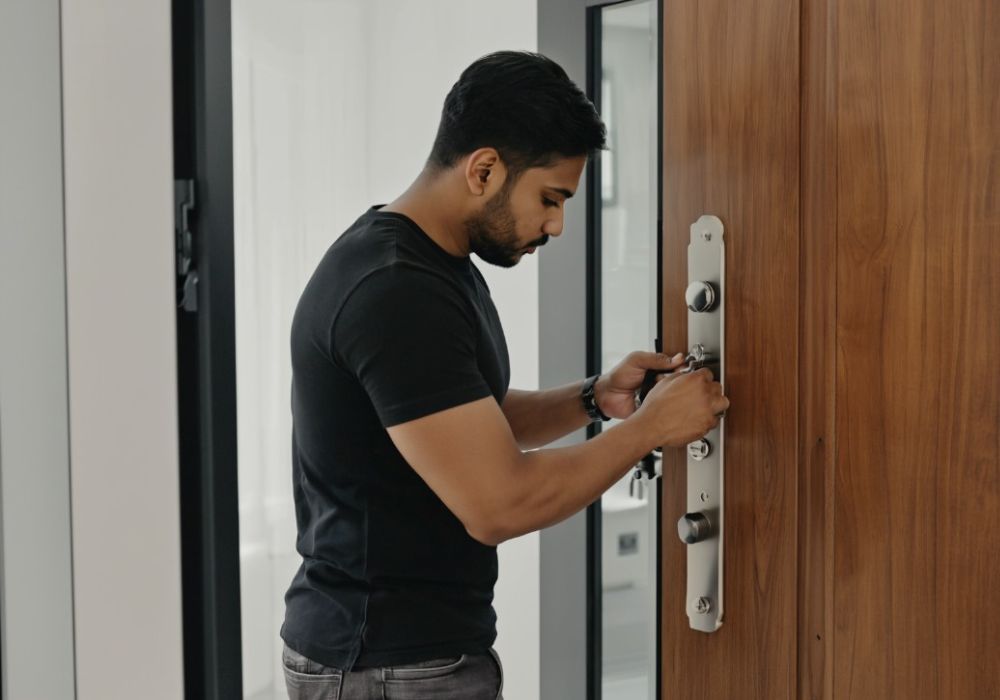 Man opent een modern meerpuntslot op een houten deur.