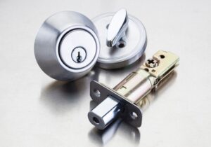 Close-up van een zilveren cilinderslot en insteekslotmechanisme op een metalen oppervlak.