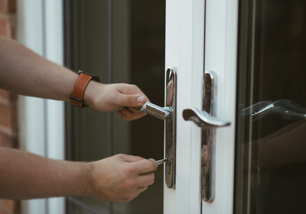 Man vervangt slot in witte kunststof deur met dubbele handgrepen.