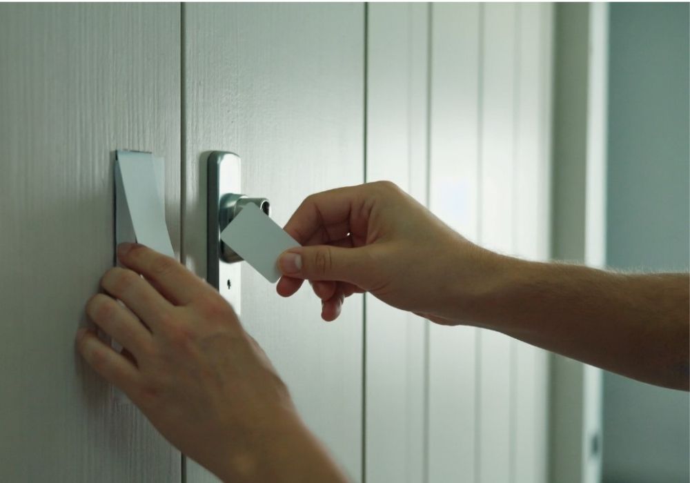 Handen proberen een deur te openen met een plastic pasje als alternatief voor een sleutel