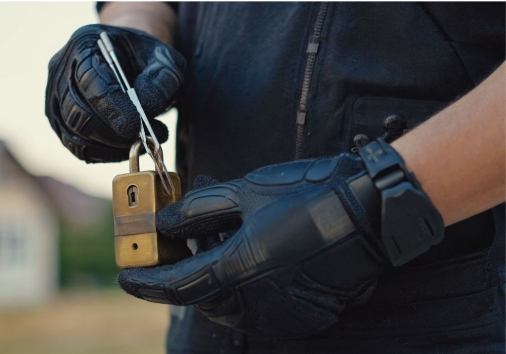 Close-up van een slotenmaker met handschoenen die een hangslot opent met speciaal gereedschap